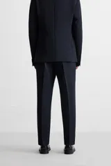 Pantalón de vestir azul marino, de corte slim fit, con bolsillos laterales y traseros de vivo con botón. Se ajusta a la cintura con cierre frontal con cremallera y botón.