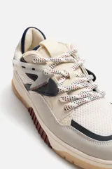 Zapatilla urbana de cordones con capellada de cuero sintético y malla en tonos beige, gris, azul marino y bordó. Suela de goma color caramelo con detalles en bordó.