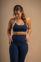 Top deportivo azul marino con tirantes blancos y logo bordado en el centro.