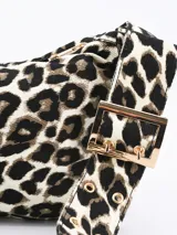 Cartera bandolera con estampado animal print en tonos grises y negros. Tiene correa corta ajustable con hebilla dorada y cierre superior con cremallera dorada.