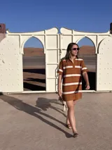 Vestido corto tejido de punto con cuello polo, manga corta y diseño a rayas horizontales en tonos marrón, naranja y blanco.