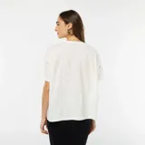 Camiseta blanca de algodón con cuello redondo y mangas cortas. Presenta un bolsillo en el pecho con dos lazos decorativos.