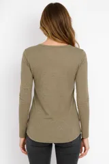 Remera de manga larga entallada en color blanco, confeccionada en algodón. Presenta cuello redondo con una hilera de botones frontales y un pequeño bolsillo en el pecho con detalle de botón.