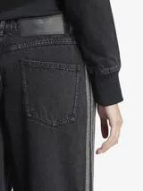 Pantalón de jean Adidas, corte ancho, color negro con las tres tiras blancas a los costados.