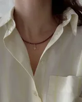 Gargantilla de cuentas facetadas color borgoña con cierre de mosquetón dorado y cadena de alargue. Incluye cuatro dijes colgantes dorados: cerezas con strass rosa, frutilla roja, corazón rojo esmaltado y estrella con strass.