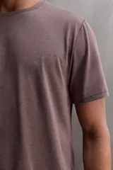 Camiseta color crema de corte relaxed fit, cuello redondo y manga corta. Tiene un texto estampado en el frente y un logo estampado en el ruedo.