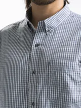 Camisa celeste y blanca a rayas verticales, de manga larga y corte clásico. Tiene cuello abotonado y bolsillo en el pecho.