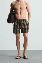 Bañador corto de tejido técnico con rayas verticales en tonos negro, verde oliva y rosa. Cuenta con cintura elástica ajustable con cordón, bolsillos laterales y trasero.