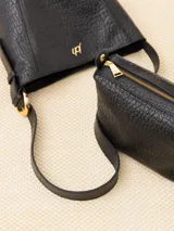 Cartera tipo tote confeccionada en cuero vacuno color crudo, con textura tipo piel de cocodrilo. Tiene correa larga al hombro y apliques metálicos con el logo de la marca. Incluye sobre interno desmontable con cierre.