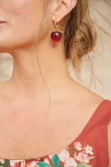 Aros colgantes con forma de manzana roja brillante y detalles dorados.