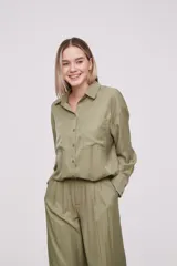 Camisa holgada de manga larga, color verde militar, con cierre frontal y dos bolsillos en el pecho.