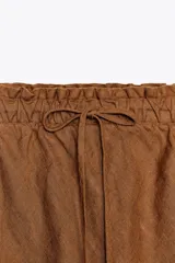 Falda midi color marrón confeccionada en lino 100%. Tiene tiro medio, cintura elástica ajustable con cordones y bajo evasé.