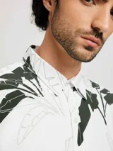 Camisa blanca de manga corta con estampado de hojas en negro y gris, cuello clásico y corte recto.