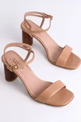 Sandalias de cuero negro con tacón cilíndrico de madera y tira fina con hebilla al tobillo.