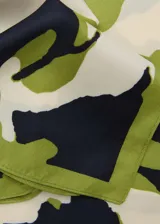 Pañuelo cuadrado con estampado de flores en tonos blanco, verde y naranja sobre fondo azul marino.