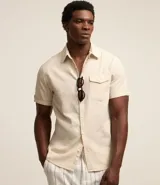 Camisa de hombre de manga corta confeccionada en una mezcla de lino y algodón, marca Marfinno. Presenta un calce confort, cuello clásico, cierre frontal con botones y un bolsillo de parche con solapa en el pecho. Las mangas cuentan con un detalle de dobladillo.