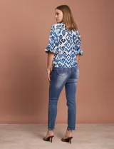 Blusa blanca de gasa marca Sioni, con cuello a la base y escote en V. Tiene abertura central con botones y mangas 3/4 con terminación fruncida.