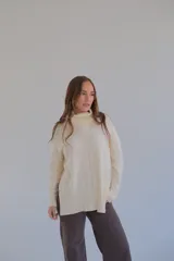 Sweater color crema de corte recto con cuello alto y aberturas laterales.