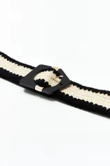 Cinturón de rafia color crudo con borde negro y hebilla geométrica negra con detalles dorados.