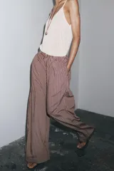 Pantalón de tiro medio con cintura elástica y bolsillos laterales ocultos en costura. Pierna ancha y estampado a rayas verticales color borgoña y blanco.