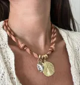 Gargantilla con cordón doble en tonos naranja y gris, con dije de concha dorada y dije de caracol blanco.