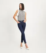 Pantalón skinny jeans azul oscuro con trabillas en la cintura, bolsillos y detalle de pespuntes contrastantes. La pieza también tiene dos botones dorados a cada lado de la barra.