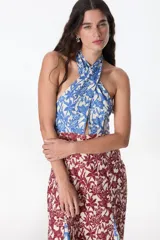 Vestido midi con estampado floral en tonos azul, rojo y beige. Tiene cuello halter con abertura en el pecho y falda con abertura lateral.