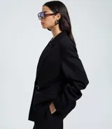 Blazer negro de mujer, modelo largo, con solapas y cierre cruzado de doble botonadura.