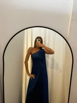 Vestido largo de tafeta con brillo, color gris o plateado, con escote asimétrico de un solo hombro y una pieza de seda liviana que cae como una capa o chal.