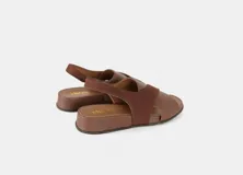 Sandalia de cuero color marrón con tiras cruzadas y talón con elástico interno.