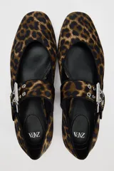 Zapato plano tipo bailarina con estampado animal, tira sobre el empeine con hebilla metálica y punta redondeada.