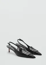Zapato destalonado negro con punta fina, detalle de flecos y calados, y cierre de hebilla. El tacón mide 5 cm.