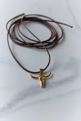 Dije plateado con forma de cráneo de toro con orificio en la frente.