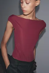 Body negro de poliamida con cuello barco, manga corta y cierre con broches a presión en la parte inferior.