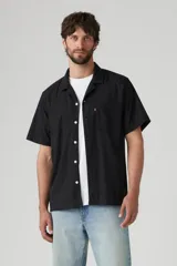 Camisa de manga corta negra con botones blancos y cuello cubano. Tiene un bolsillo en el pecho izquierdo con el logo de Levi's en rojo.