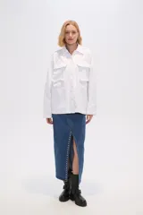 Chaqueta blanca de algodón con cuello camisero, cierre frontal con botones, bolsillos de parche y frunces en los hombros.