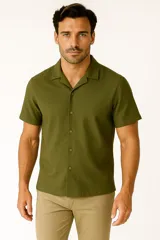 Camisa de lino color verde militar, de corte holgado, con cuello tipo solapa, botones frontales y manga corta.