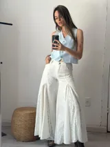 Pantalón blanco de corte palazzo con aplicaciones de encaje floral en los laterales.