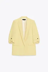 Blazer color marrón oscuro, de corte recto, con cuello solapa y hombreras. Tiene mangas 3/4 con trabilla y botón dorado, y bolsillos delanteros con solapa.