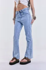 Jean de denim celeste, de corte recto y tiro medio, sin lycra. Presenta tachas metálicas en los laterales.