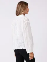 Camisa de algodón blanca con bordados florales verticales, cuello con solapa y cierre frontal con botones.