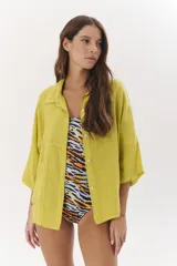 Camisa de lino color verde lima, de manga corta y corte holgado, con cuello camisero y bolsillos frontales.