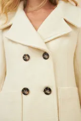 Chaquetón color crema con doble solapa, abrochadura doble, bolsillos delanteros y forro al tono.