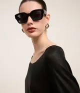Blusa negra de punto liviano con escote redondo, manga larga y sisa raglán. Tiene una malla con lámina metálica.