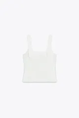 Top blanco de tejido elástico con escote cuadrado y tirantes anchos con lazos decorativos.