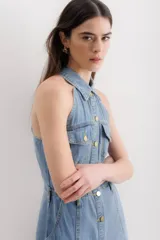 Vestido midi de denim celeste, con cuello camisero halter, botones dorados en el frente, bolsillos en el pecho y falda acampanada.