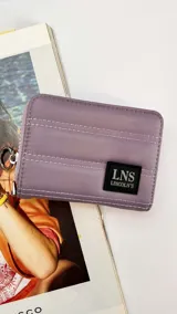 Billetera corta con cierre alrededor y tapa, confeccionada en tela capitoneada. Incluye varias reparticiones con tarjeteros y bolsillos internos, y una correa de mano desmontable. Disponible en negro, rojo y dorado.