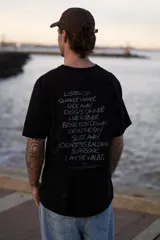 Remera negra de manga corta con cuello redondo y corte holgado. Estampa en la espalda con los títulos de canciones de la banda británica Oasis.