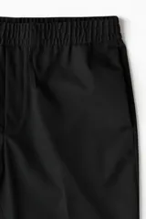 Pantalón negro de sarga con cintura elástica y cordón ajustable, corte slim fit, largo tobillero y dobladillo en el bajo.