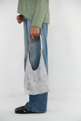 Bolso mini tote de cuero blanco craquelado, con correa de hombro y cierre superior.